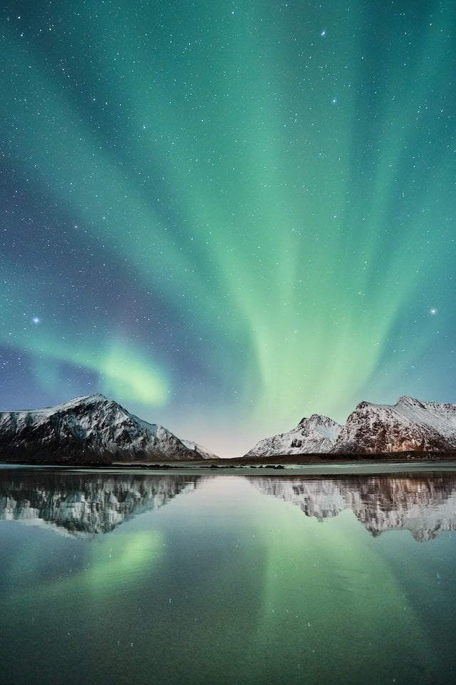 Northern lights and stars over mountains and lake