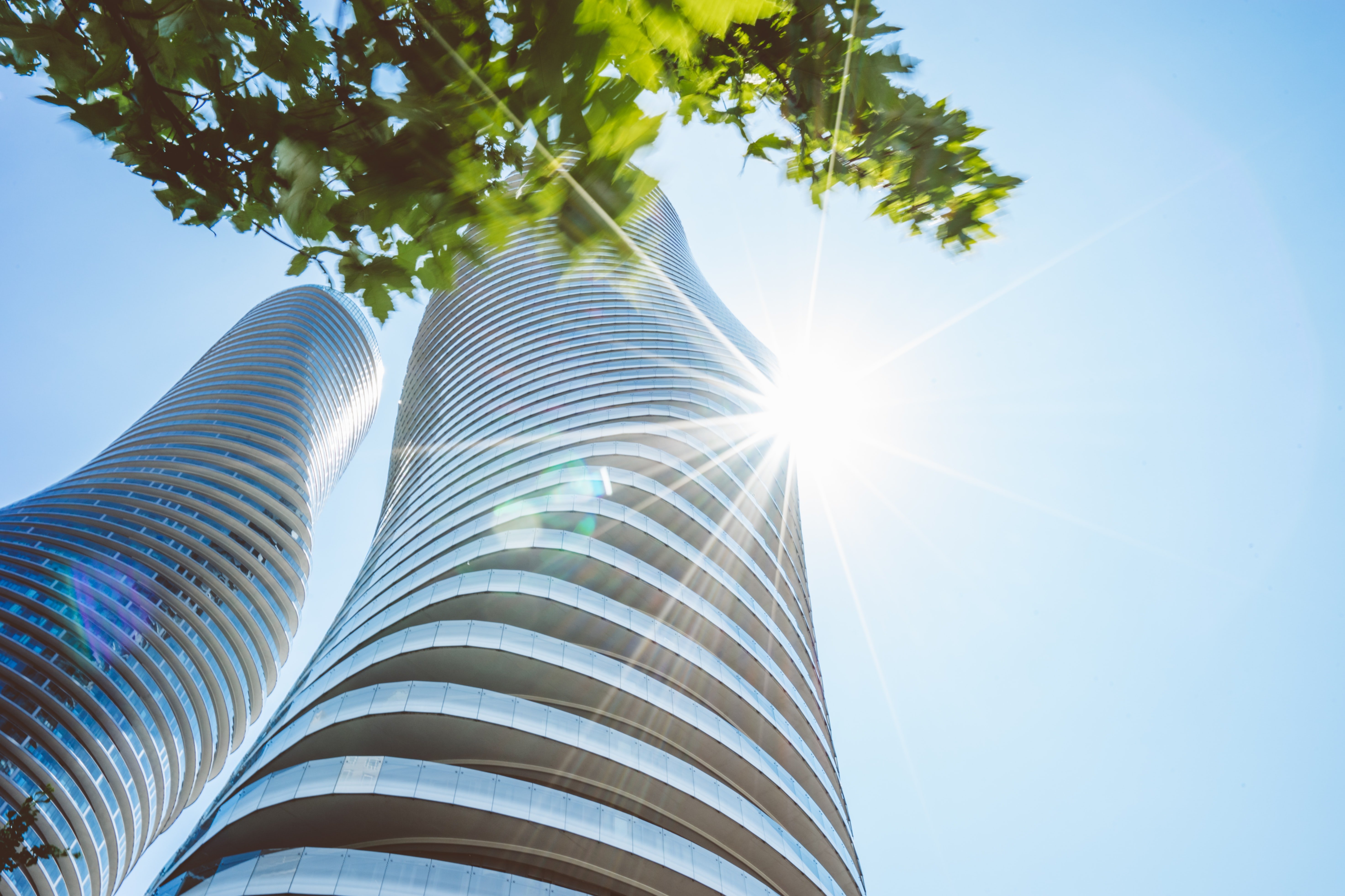 Two tall glass buildings covered in sunshine